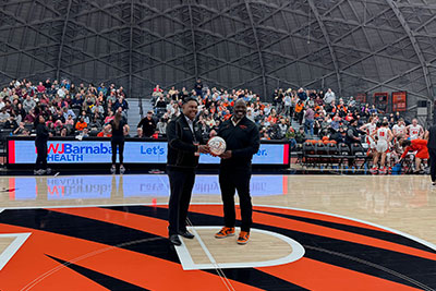 Dr. Horana and John Mack standing on the Princeton basketball court, Dr. Horana and John Mack are holding a basketball together